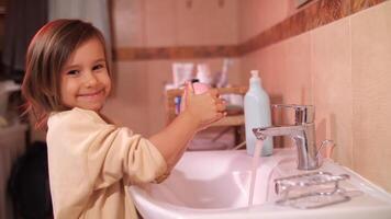 flicka tvålar henne händer med en bit av rosa tvål i de badrum video