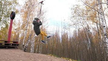 A boy begins his descent on a zip line in the fall. Boy having fun video