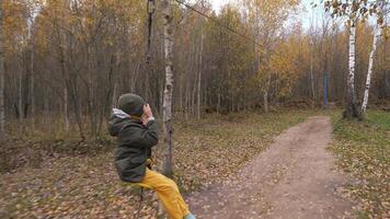 a boy rides a zip line in the fall. Autumn colors. unsafe descent on a zip line video