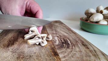 dichtbij omhoog beeld van een persoon snijden vers wit champignons Aan een houten snijdend bord, perfect voor culinaire concepten en gezond aan het eten thema's video