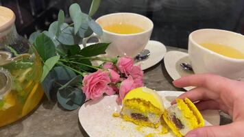 Lemon macarons female hand carelessly crumbles and cuts macarons with french dessert with knife on a glass table close-up yellow lemon. macarons with poppy seed filling video