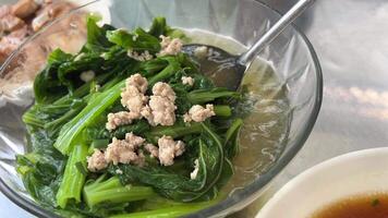 Top view of bowl with cooked spinach on table Vietnamese soup with green leaves and pieces of meat video