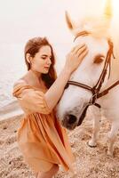 A white horse and a woman in a dress stand on a beach, with the photo