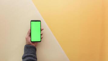 vista superior de la mano de un joven usando un teléfono inteligente con pantalla verde video
