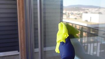 hand in blue glove cleaning window with green rag video