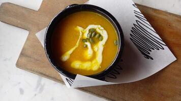 Delicious pumpkin soup in bowl on wooden table, video