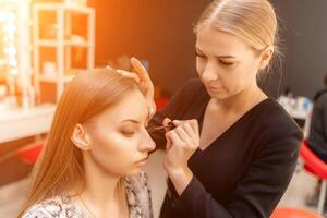 Makeup artist paints eyelashes to a woman in a beauty salon. photo