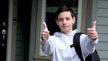 boy schoolboy shows thumbs up shows with both hands thumbs down spreads arms to sides What to do on shoulder backpack against private sector teenager sporty sweatshirt black hair European teenager video