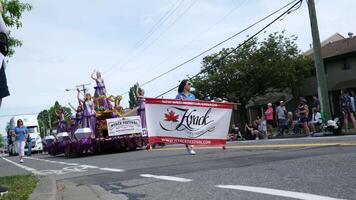 Cloverdale Nyack Festival Kmck beautiful women in lilac dresses with a crown and beauty queens are driving a car along the street of a gay parade waving their hands with ribbons smiling applauding video