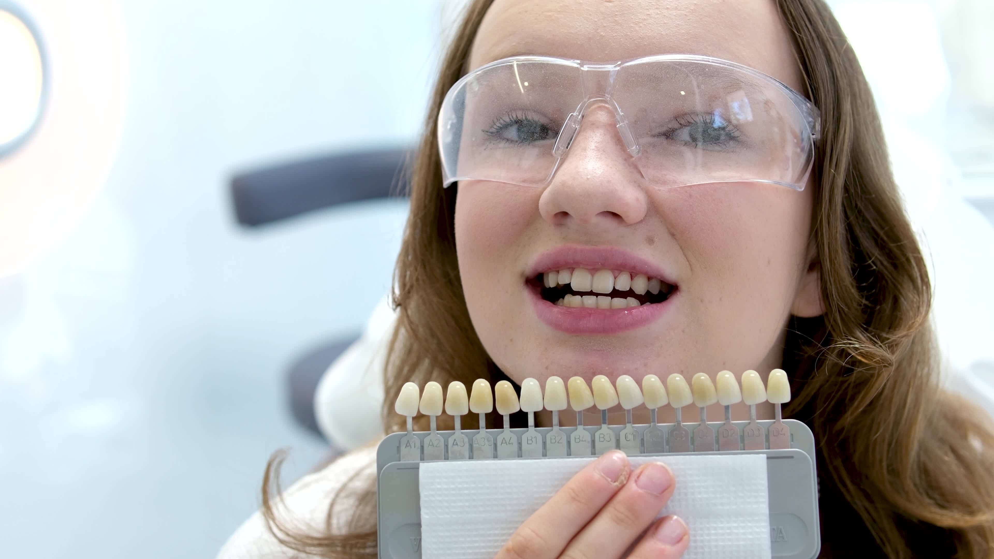 tooth whitening, perfect white crown teeth close up with shade guide