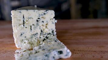 rotazione formaggio su nero ardesia piatto. delizioso formaggio dorblu su il taglio tavola su sfondo video