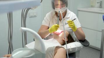 dentistry adolescence a doctor in yellow gloves fills a tooth of a young girl for a woman close-up in dentistry at the dentist drying the tooth with light new technologies modern clinic video