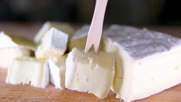 Komposition von Italienisch Käse, auf ein hölzern Schneiden Tafel. einer Hand nimmt das Messer und geht kaputt ein Paar von Stücke zu genießen das Qualität. video