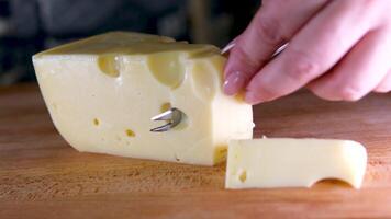 femmina mani taglio formaggio con un' coltello su un' di legno taglio tavola. video