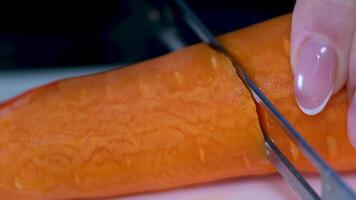 Frau schneidet Möhren mit ein Koch Messer auf ein hölzern Planke, Nahansicht gesund Diät Essen video