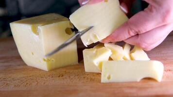 fêmea mãos corte queijo com uma faca em uma de madeira corte borda. video