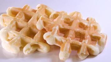 Belga waffles dentro uma branco prato em uma luz de madeira fundo. waffles sem enchimento. video