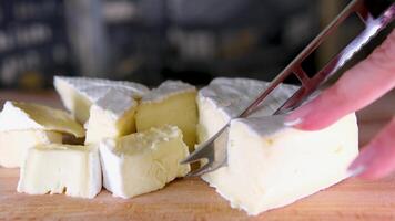 samenstelling van Italiaans kaas, Aan een houten snijdend bord. een hand- duurt de mes en breekt een paar van stukken naar genieten de kwaliteit. video