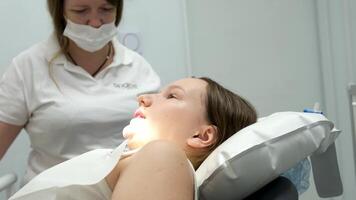 dentistry adolescence a doctor in yellow gloves fills a tooth of a young girl for a woman close-up in dentistry at the dentist drying the tooth with light new technologies modern clinic video