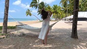 Woman dancing, running, hair and pareo fluttering woman on tropical seashore between palms Elegant woman enjoying summer travel in bikini wearing sunglasses. Pretty stylish lady wearing sun hat. video