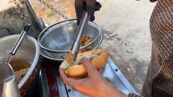 Cheap street food in Vietnam buy a bun Vietnamese woman stuffing a bun with different ingredients to fry Overcooked bad food is bad for health and dangerous video