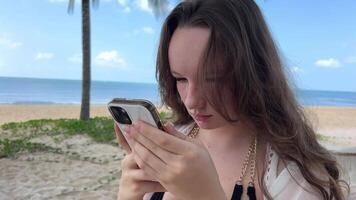 dyr hotell resa annons chic lyx strand en ung kvinna flicka i en vit pareo svart baddräkt danser lögner vilar drycker vatten utseende på de telefon användningar mobil nät på de hav hav video