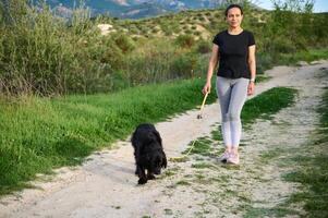 Full size shot of beautiful happy smiling woman walking her dog in mountains nature outdoors. photo