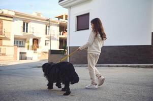 Happy adorable little child girl walking her dog on leash on the city street. Pets and children. Playing pets concept photo