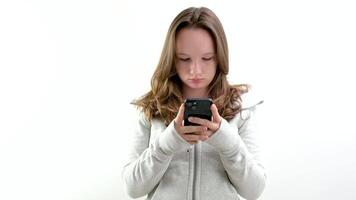 Giochi su il Telefono un' giovane ragazza è occupato digitando testo o scrittura un sms utilizzando il Internet Wi-Fi bellissimo persone adolescente adolescenza comunicare con amici sociale reti essere occupato con gadget video