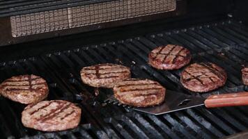 hamburgers Koken Aan barbecue rooster met vlammen Aan een rooster zijn voor de helft gebakken fijngehakt gehaktballen voor een eigengemaakt hamburger achtergrond voor bbq in de zomer met houtskool en vers gehaktballen video