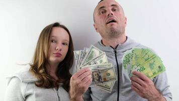 father and daughter a lot of money in their hands joy success dollars euro 100 dollar bill wave money like a fan look into the frame make faces confidence success big win purchase gift video