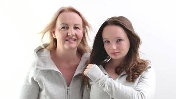 hermosa personas dos mujer madre y hija Mira dentro el marco y luego a cada otro sonrisa sensibilidad idéntico ropa modelos en blanco antecedentes en estudio risa sonrisa toque nariz a tu mejilla video