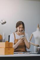 Starting Small business entrepreneur SME freelance, Portrait young woman working at home office, BOX, smartphone, laptop, online, marketing, packaging, delivery, b2b, SME, e-commerce concept.. photo