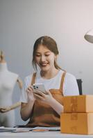 Starting Small business entrepreneur SME freelance, Portrait young woman working at home office, BOX, smartphone, laptop, online, marketing, packaging, delivery, b2b, SME, e-commerce concept.. photo