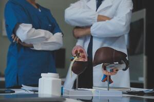 médico, reunión y ordenador portátil para equipo en oficina en discusión, lluvia de ideas y planificación. doctor, enfermero y computadora en escritorio, trabajo en equipo o taller para modelo interno Organo. foto