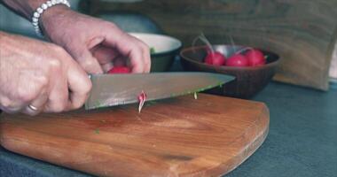 vår sallad. rädisor, dill, sallad. man skärande sallad på en trä- styrelse video