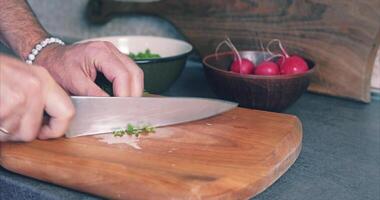 A man cuts spring salad with bracelets on his hand. Radishes, lettuce, dill in a clay plate video