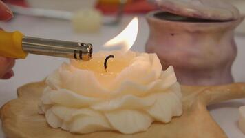 The lighter ignites a candle, light a candle hand with match sets fire to scented pink wax candle on a gray background video
