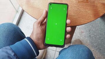ung man hand med smart telefon med grön skärm på café video