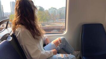 European girl with blond long hair in a white shirt rides in a skytrain she sadly looks out the window she is sad waiting for her A long road outside the window flashes nature houses Vancouver Surrey video