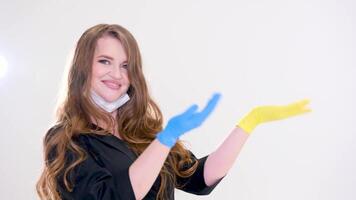 kvinna läkare i masker på haka i gul blå handskar poäng till ett tömma Plats för text lång strömmande hår skön smink svart kläder reklam skön flicka personlig vård behandling hjälp ukraina video