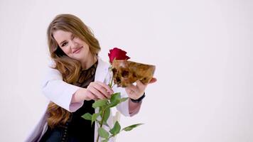 mooi vrouw in wit gewaad en zwart sexy kleren Aan wit achtergrond met rood roos en menselijk schedel concept leven en dood schoonheid en oud leeftijd geneeskunde behandeling herstel ziekte verdovende middelen advertentie video