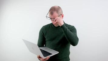 adult man with laptop wearing glasses looks at screen vision has fallen age-related problem is bad seeing put glasses on nose eye treatment vision correction white background ad space text see light video