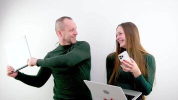 man and woman are fighting using laptop tablet and phone technology laugh play jokes on white background husband and wife teacher and student father and daughter Sensei waving magazine green sweater video