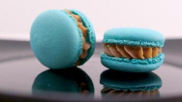 two blue macaroons on a black plate with reflection one swirls the other lies motionless relationship delicious food breakfast lunch Blue macaroon isolated on white background video