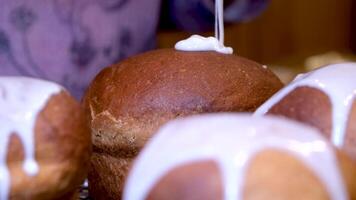 närbild kök spatel utstryker vit glasyr på utsökt ortodox påsk bröd, en traditionell ryska och ukrainska påsk kaka för östra Europa. påsk kaka på en grå bakgrund. video