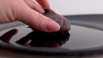 ein weiblich Hand setzt auf ein Teller ein schön lockig Mäusespeck im Schokolade ein köstlich Dessert Betrachtung auf ein Teller oben Aussicht von Schokolade bedeckt Plätzchen isoliert auf Weiß video
