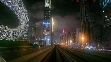 Dubai - - vereinigt arabisch Emirate 01.05.2024 Dubai Horizont beim Nacht von ziehen um Metro, ein beschwingt Nacht Aussicht von das Dubai Horizont mit beleuchtet Wolkenkratzer und ein einzigartig Halbmond Mond Skulptur von video