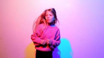 ein Kind, ein Mädchen, Tänze auf das Hintergrund von ein Mauer beleuchtet durch das Farben von das Regenbogen und das Farbe Spektrum. video