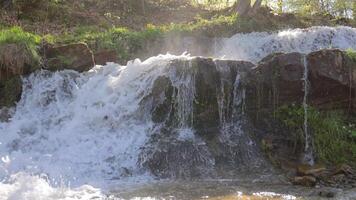 vattenfall och Fantastisk natur. de snabb strömma av de flod och stänk av vatten droppar upplyst förbi de solstråle video